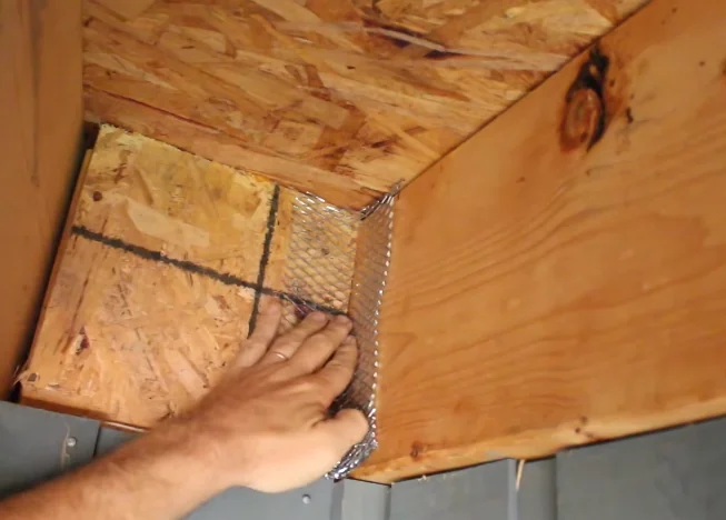 Hardware cloth being fastened into a soffit corner to keep squirrels out of an attic