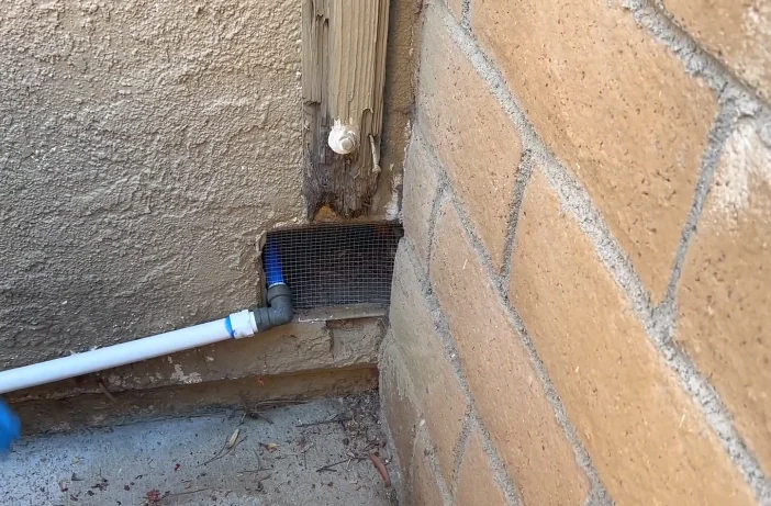 Pipe entering a brick wall with the gap sealed by mesh