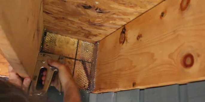 Hardware cloth being stapled across an open eave